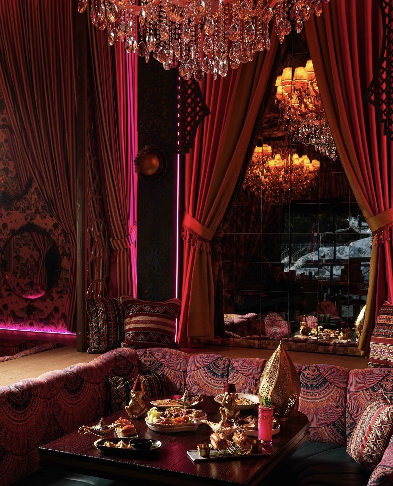 Habibi Miami River private booth velvet cushions Arabian decor crystal chandelier red drapes food spread Miami River restaurant